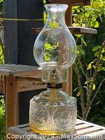 Full view of the antique oil lamp showing tall clear glass chimney and decorative base.
