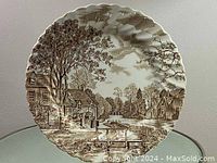 Full view of the round Johnson Brothers ceramic plate with detailed brown transferware pastoral scene and scalloped edge.