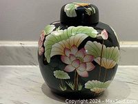 Front view of the black ginger jar showing detailed hand painted lotus flowers and leaves.