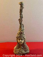 Front view of the gold-colored plaster candle holder figurine showing the detailed female face and leaf accents.