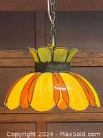 Front view of stained glass hanging lamp showing petals in green, amber, and yellow glass and metal fixtures, with chain attachment on top.