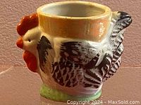 Side angle view showing rooster body with black and white feather details and orange comb and wattle with green base.