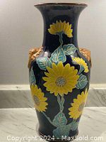 Front view of vintage ceramic vase featuring large yellow sunflowers on dark blue background with green leaves and gold rim.
