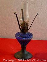 Full view of vintage oil lamp showing blue cobalt glass font, metal base, and clear glass chimney.