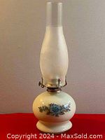 Full view of vintage oil lamp with milk glass base, clear glass chimney, and metal burner with wick adjuster.