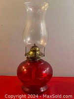 Full view of the vintage red ruby glass oil lamp showing the base, brass burner, and clear glass chimney.