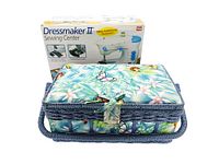 Closed vintage sewing basket with floral and butterfly fabric, woven handle and latch, displayed in front of original Dress Maker II sewing machine box