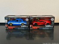 Front view of both boxed diecast cars: Brian's blue Ford Escort and Red Lykan Hypersport Lamborghini