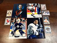 Full lot showing three large sports photos and six smaller trading cards on wood surface