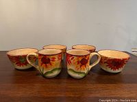 Front view of two sunflower hand painted mugs and four matching cereal bowls arranged on a wooden surface