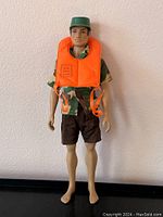 Front view of G.I. Joe action figure wearing green cap, camouflage shirt, black shorts, and bright orange air vest.