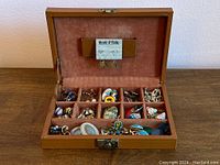 Open brown leather case showing organized compartments filled with vintage costume earrings.