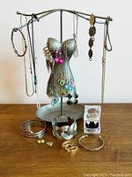 Full lot display showing all jewelry items on and around a metal torso mannequin jewelry holder. Includes necklaces, earrings, bracelets, and a small jewelry box with a pair of earrings inside.