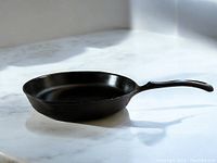 10.5 inch Wagner 1891 cast iron skillet frying pan shown on marble surface with light coming from window highlighting inside and handle shape.