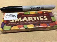 Photo of sealed Rowntree Smarties pack from 1960s alongside a Sharpie pen for scale. Pack is unopened with vintage colorful design and 10 cents price.