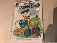 Front cover of Donald Duck #78 comic showing Donald with a lawnmower and hose.