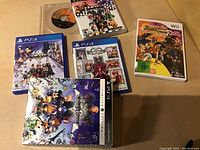 Photo showing five video game cases including Kingdom Hearts titles for PS3 and PS4, plus a Wii game. Cases have colorful animated cover art.