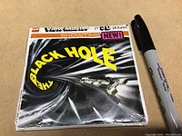 Front of sealed View-Master packet showing The Black Hole artwork and title with a Sharpie marker for scale.