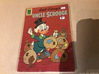 Front cover of Uncle Scrooge comic issue #37 from 1962 wrapped in protective sleeve, showing Uncle Scrooge with money bags on red background.