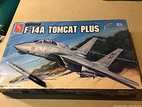 Front of unopened GM Grumman F-14A Tomcat Plus model kit box showing colorful aircraft artwork and branding.