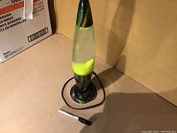 Vintage space-themed lava lamp with yellow wax lava inside clear glass bottle on black base with sci-fi graphics. Electric cord shown here unplugged.