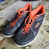 Side view of dark grey Fila runners with orange laces and logo