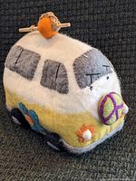 Front and side view of the felted wool VW bus birdhouse showing colorful details and rope hanger.