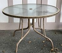 Full view of round garden table with textured glass top and metal frame with curved legs