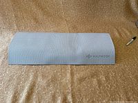 Grey Half Moon yoga mat partially unrolled on textured surface showing brand logo.
