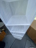 Close-up image looking into the open compartments of the white cloth shelving unit showing individual square shelves and fabric construction.