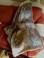 Soft, dense faux fur throw blanket draped over a sofa, showing texture and color of the fur side.