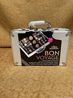 Front view of unopened The Color Institute Bon Voyage 36 piece makeup train case showing dimensions and product details on packaging