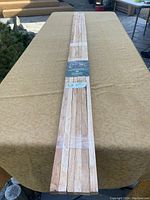 Full view of six hardwood stakes bundled together on a table, showing length and natural wood material.