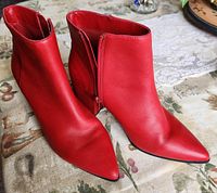 Side view of the pair of red ALDO ankle boots showing pointed toe and side zipper.