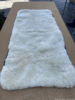 Full front view of the white fluffy sheepskin chair cover laid flat on a table.