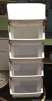 Five stackable off-white plastic storage bins stacked vertically, showing open front design and overall condition.