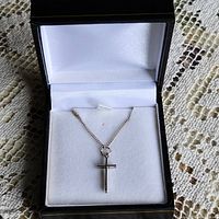 Sterling silver chain with cross pendant displayed in black jewelry box.