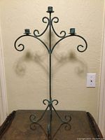 Front view of tall iron candle holder showing three candle holders and verdigris patina finish