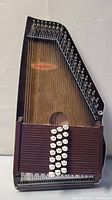Full view of Anjoharp Chromoharp showing trapezoidal wooden body with strings, tuning pegs, and chord buttons.