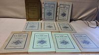 Top-down view showing full set of 10 annual softcover Delaware Masonic Grand Lodge books laid out on a table with covers fully visible in various colors and featuring Masonic emblem