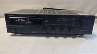 Full front view of Denon DRA-335R AM FM stereo receiver powered on showing frequency on LED display and control panel.