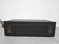 Front view of SIMA power amplifier Model W-3050 showing black metal face with gold design details, SIMA logo, and power switch with red LED indicator light.