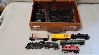 Lot overview in brown carrying case showing train tracks, power adapters, and train cars inside.