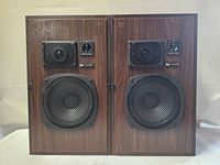 Front view of the pair of DUAL CL-450 speakers showing the woofer and tweeter drivers behind mesh grills with volume knobs and model labels.