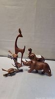 Photo showing all four wooden animal sculptures together: giraffe, rhino, elephant, and birds