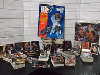 Photo showing multiple stacks and piles of basketball cards with various players, and a boxed SkyBox Shaquille O'Neal action figure