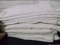 Stack of folded white or off-white cloth shower curtains.