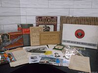 Wide shot showing assortment of vintage books, pamphlets, handwritten papers, and other ephemera spread out on table.
