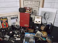 Photo showing a variety of vintage cufflinks, tie clips, old books, and printed materials laid out on a surface