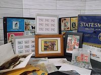 Overall view showing the Statesman Deluxe Album, framed stamps, loose stamps in envelopes and sheets spread out